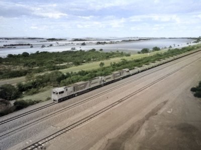 A long train travels on a track with fields and open country either side of it.